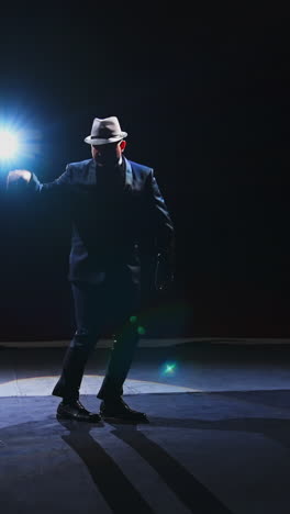 artist dancing on scene. theatrical man in elegant suit and hat performing on stage in spotlight. entertainment concept. vertical video