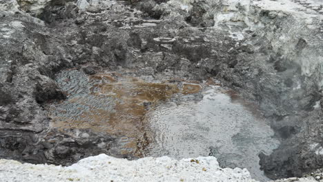 disparo de arriba hacia abajo piscina de agua clara burbujeando lentamente en el valle volcánico, cerrar