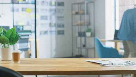 wooden desk in the creative bright office. in the background professional young man working on computer