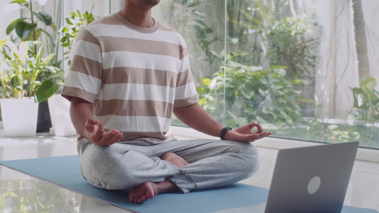 Man Practicing Meditation in Yoga Pose Using Laptop