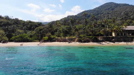 Vista-Aérea-Lejos-De-Una-Playa,-Sobre-El-Mar-Turquesa,-En-El-Parque-Natural-Nacional-De-Tairona,-Colombia---Tire-Hacia-Atrás,-Tiro-De-Drones