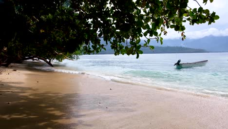 small motorboat moored with gentle waves lapping onto beach of remote tropical island landscape in bougainville, papua new guinea