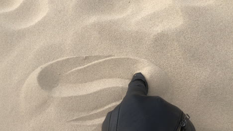 모래에 파도를 그리는 검은 장갑의 샷