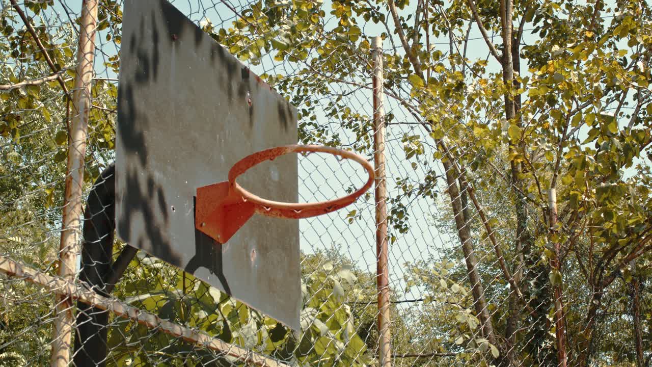 pelota naranja atravesando la canasta redonda con tablero de acero de baloncesto en cámara lenta