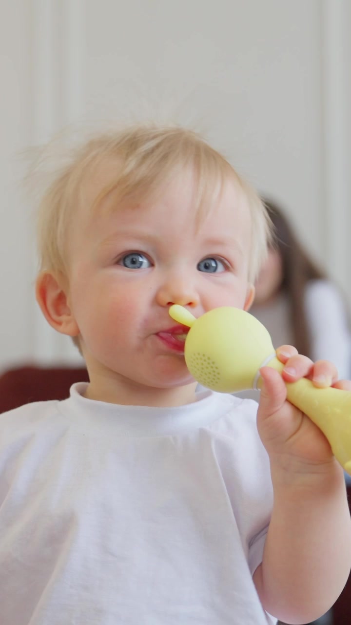 Adorable Toddler Chewing on a Yellow Toy Microphone
