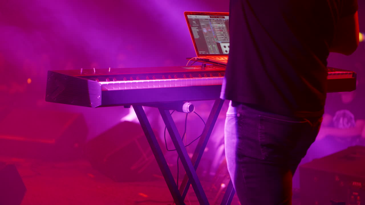 Musician Performing on Stage with Keyboard and Laptop