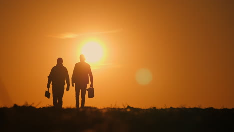 silhouette of two people walking at sunset