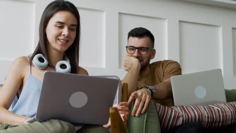 estudiante hablando con una compañera sentada en un sofá mientras mira una laptop