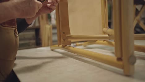 slow-motion-video-of-hands-of-leather-craftsman-while-screwing-screw-on-chair