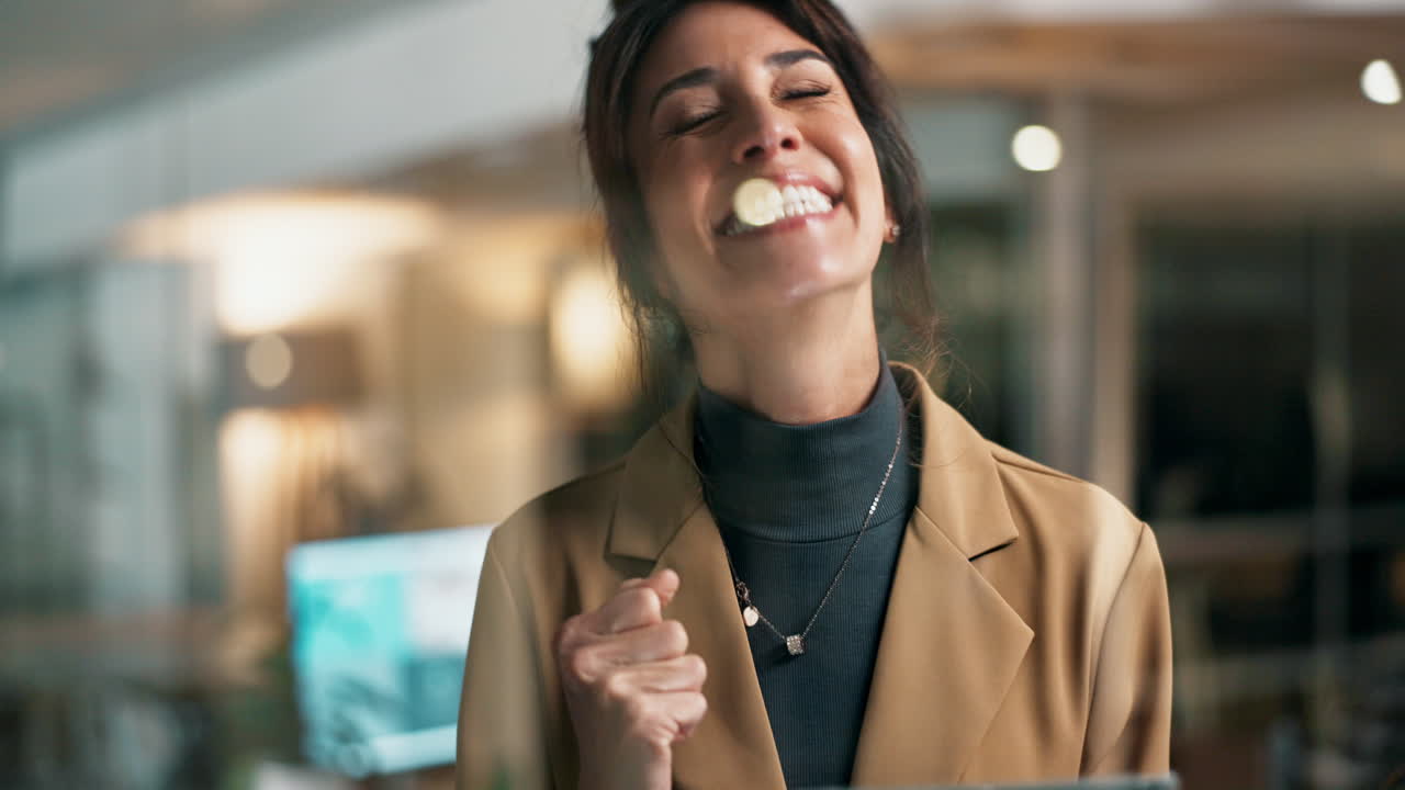 Excited businesswoman celebrating success with tablet in office