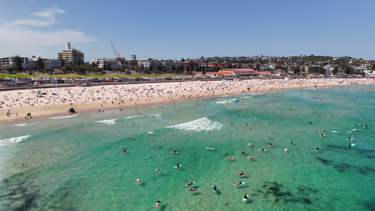 Drone shot of Bondi Beach, showcasing people surfing, sunbathing, and relaxing along the coastline. Aerial view, NSW, Australia