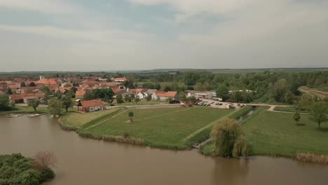 fpv drone above bernhardsthal's railway stone bridge as a freight train traverses it over a tranquil lake