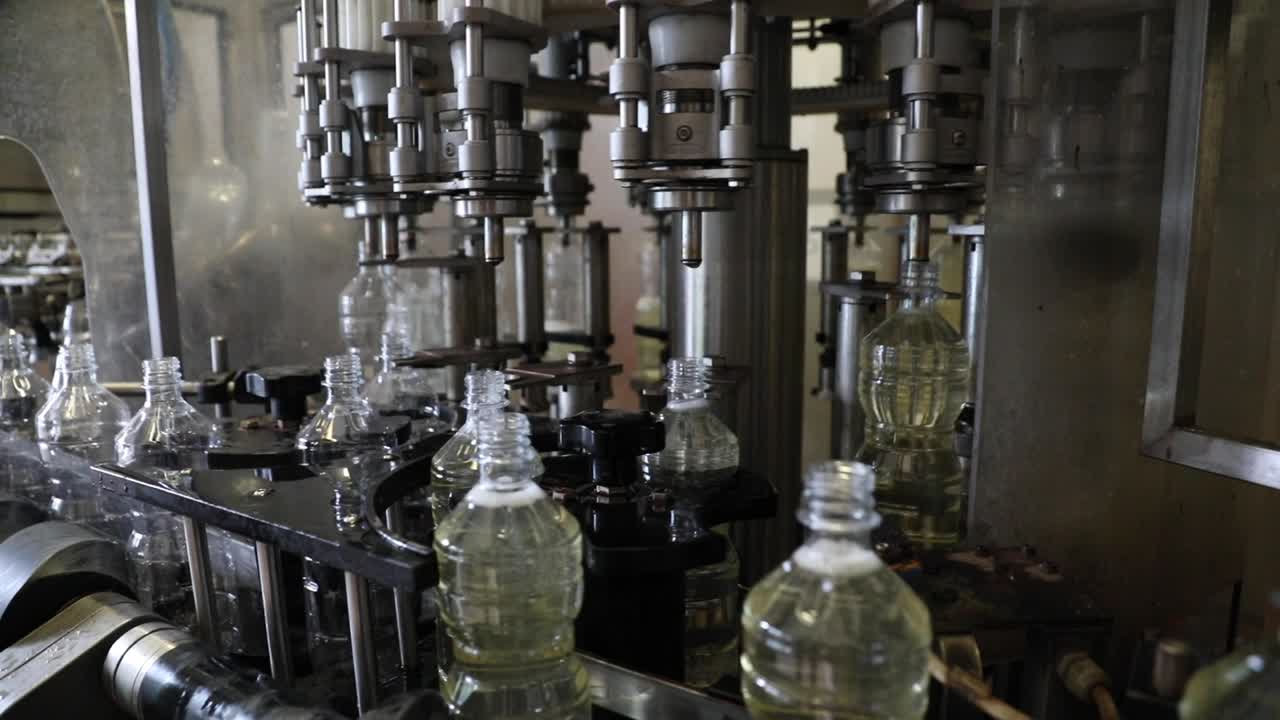 Plastic bottles rotate on an automated machine as they are filled with fresh vinegar at a factory processing plant