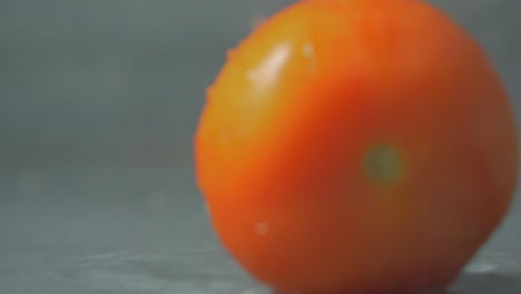 red tomato falling and splashing on water, close-up blurred