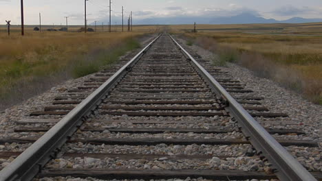 las vías del tren se extienden a través de una llanura cubierta de hierba hacia el horizonte