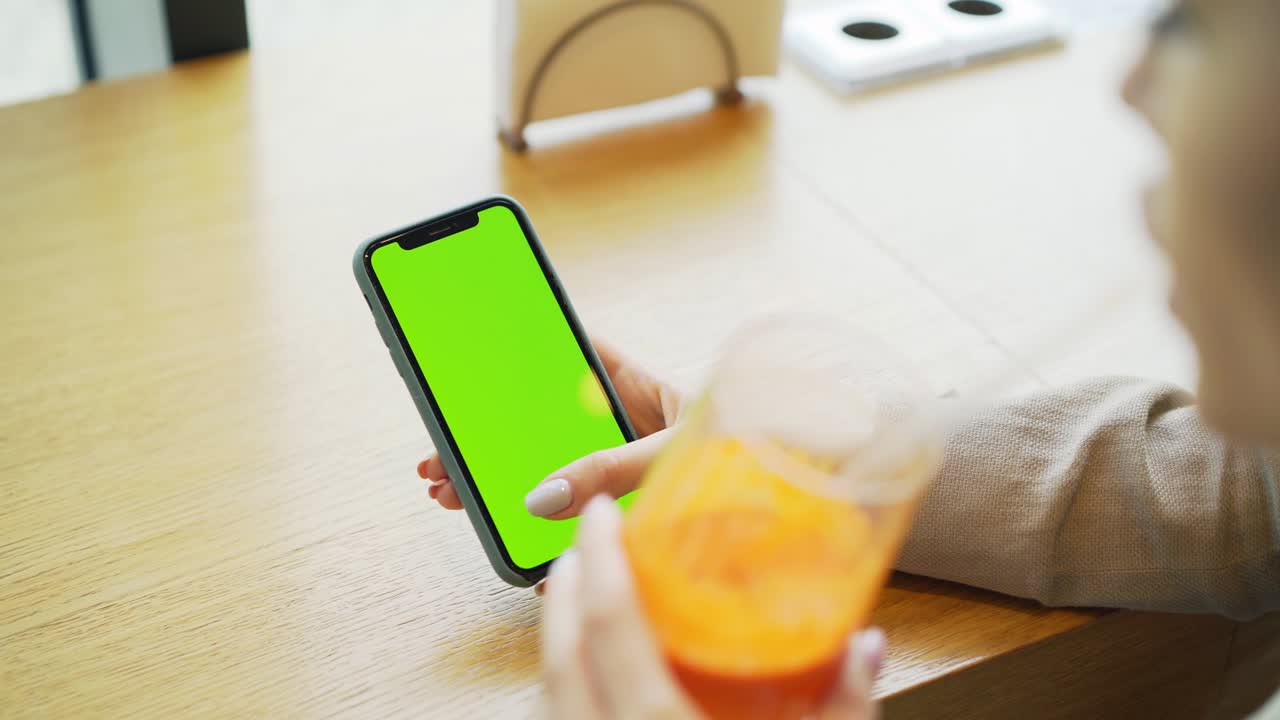 faceless woman drinking orange juice in cafe