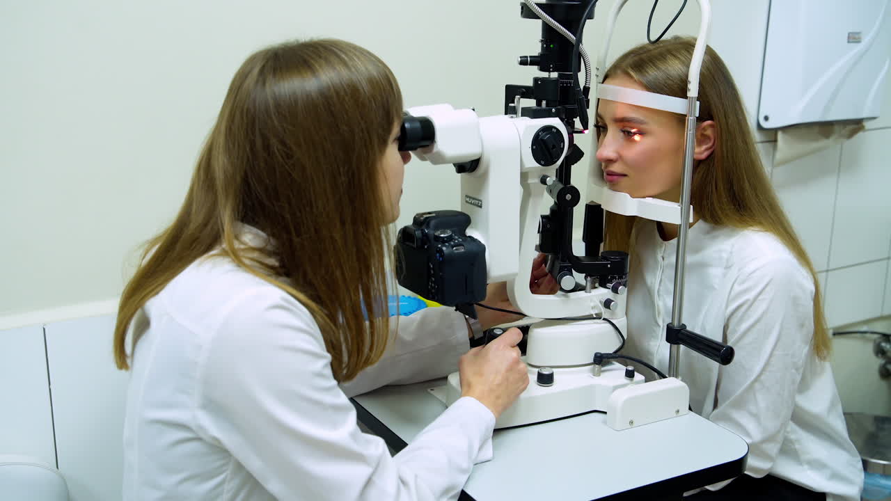 Eye care medical diagnostic. Portrait of female ophthalmologist using refractometer while checking eyesight of woman in modern clinic