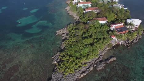 Un-Promontorio-Rocoso-Se-Adentra-En-Aguas-Cristalinas-De-Arrecifes-De-Coral-En-El-Caribe,-Roatán