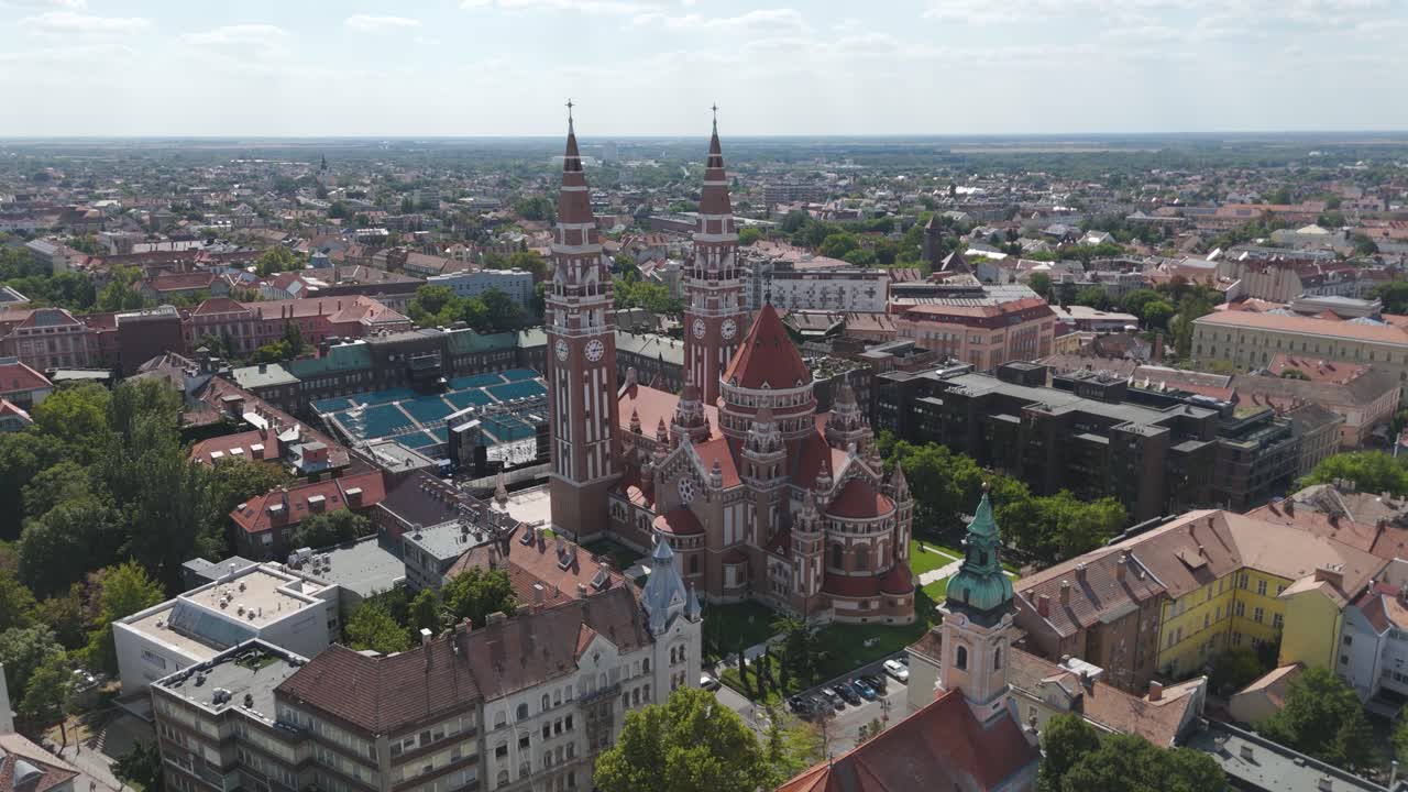 Drone orbit around the Votive Church of Szeged, highlighting its striking red-brick architecture and twin towers from above