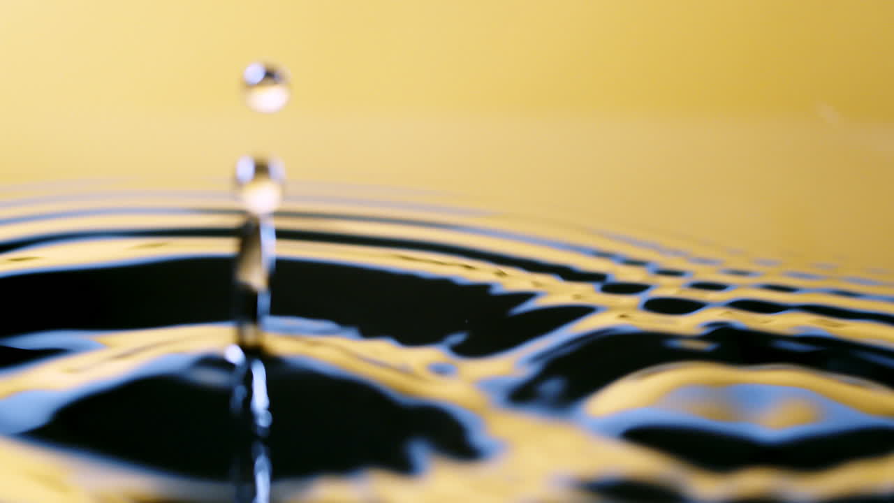 Close up real of water drop falls into water and diverging circles of water with smoot color background in studio with copy space for place a text for advertisement.