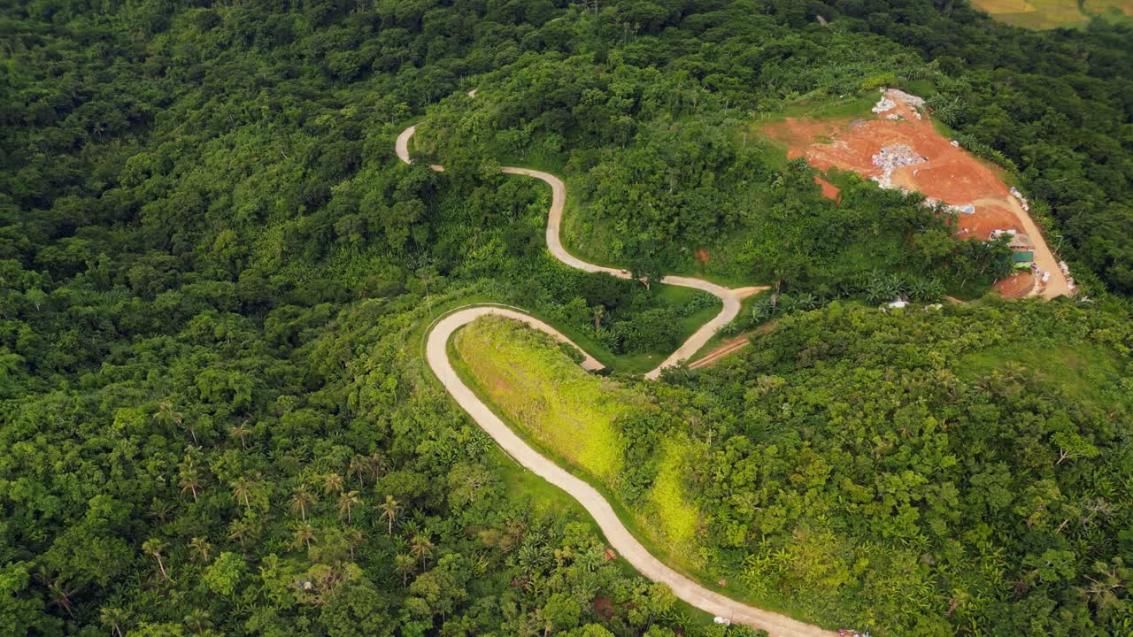 Picturesque aerial flyover shot of winding roads along lush tropical mountains at the province island Catanduanes, Philippines during daytime