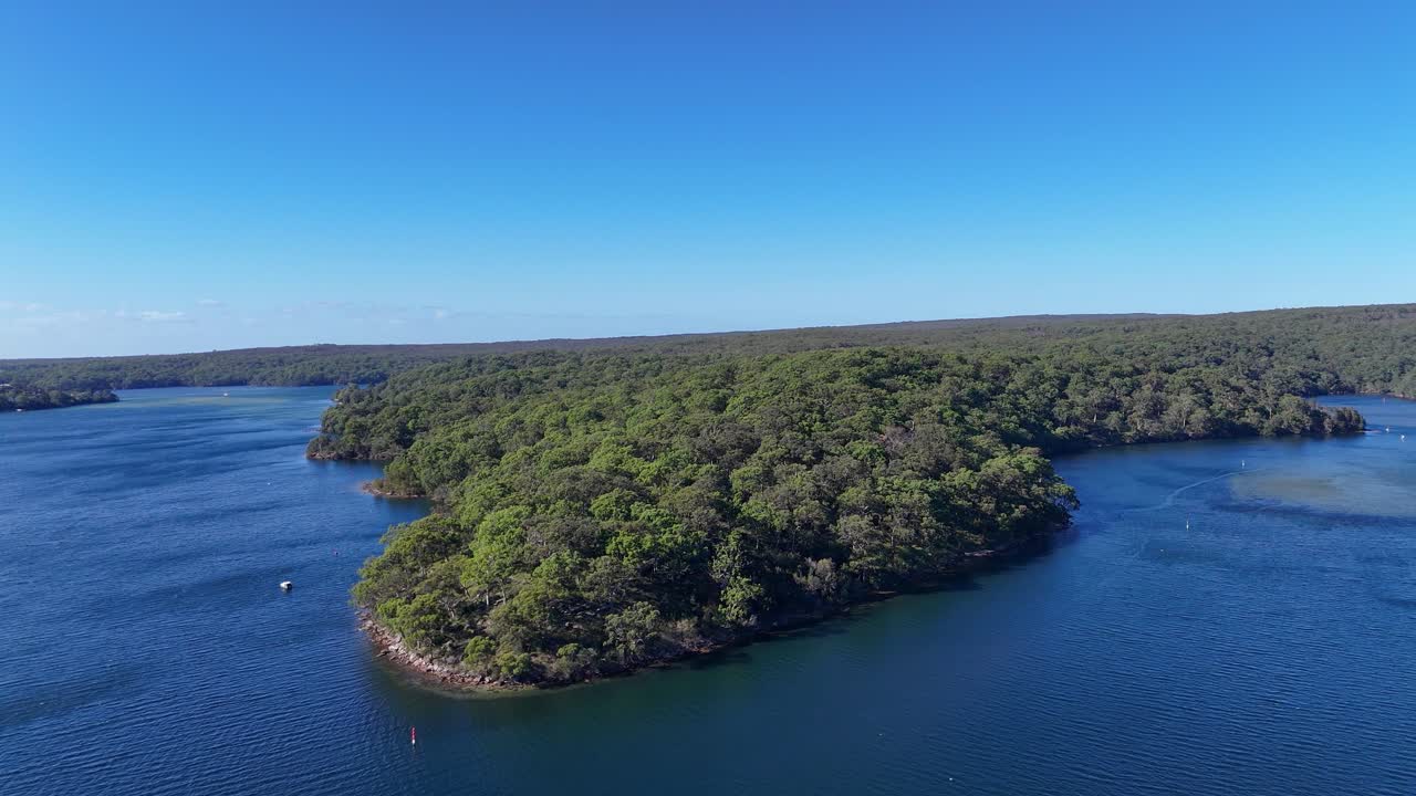 Aerial orbit of calm blue water at Gymea Bay surrounded by bushland and shoreline