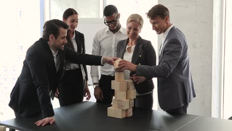 un equipo multiétnico juega un juego de construcción de equipos construye una torre con cubos