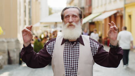 retrato de un anciano orando con los ojos cerrados a dios pidiendo bendición ayuda perdón al aire libre