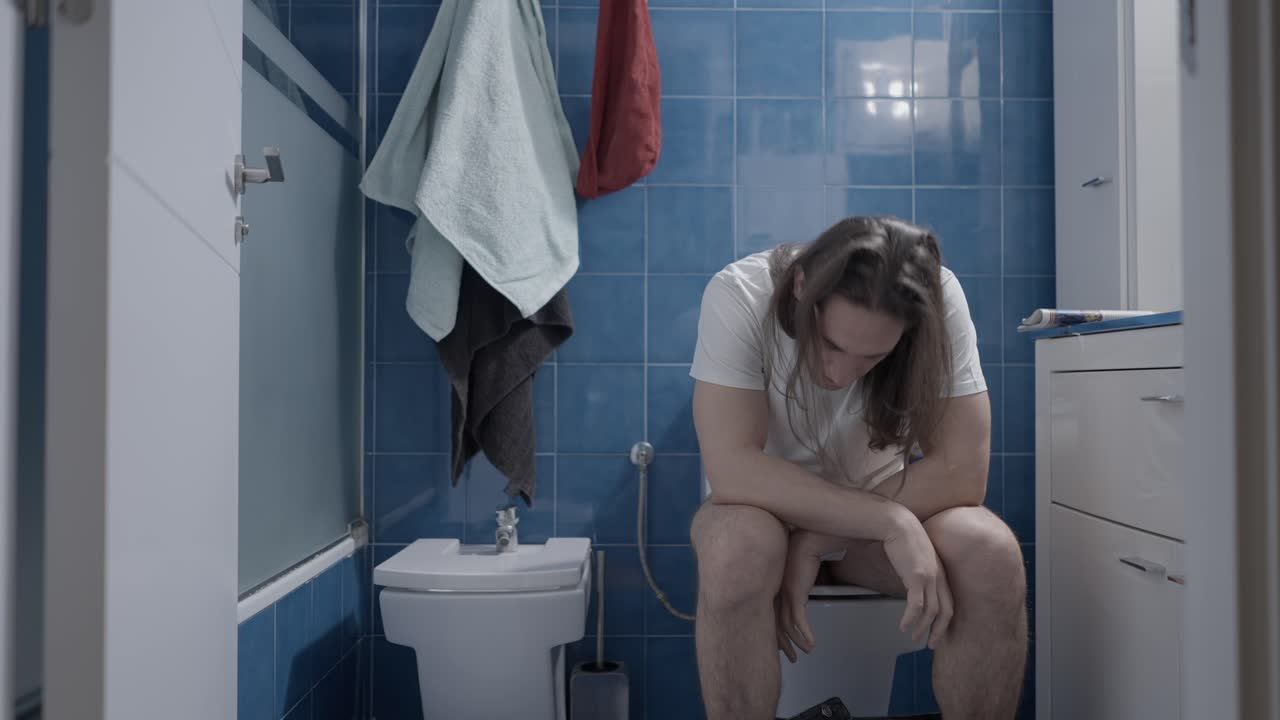Man Sitting on Toilet in Bathroom