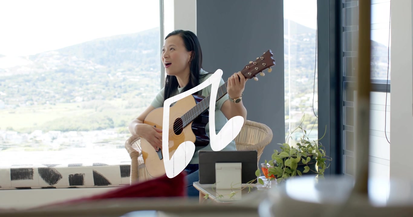 Donna che suona con un top verde chiaro e pantaloni scuri che strimpella la chitarra vicino a una finestra, grafica di una nota musicale bianca