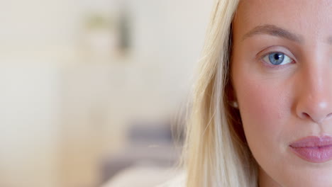 close-up of woman with blue eyes and blonde hair, looking thoughtful at home, copy space