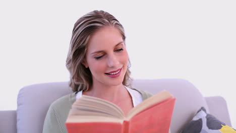 concentrándose mujer atractiva sentada en el sofá mientras lee un libro