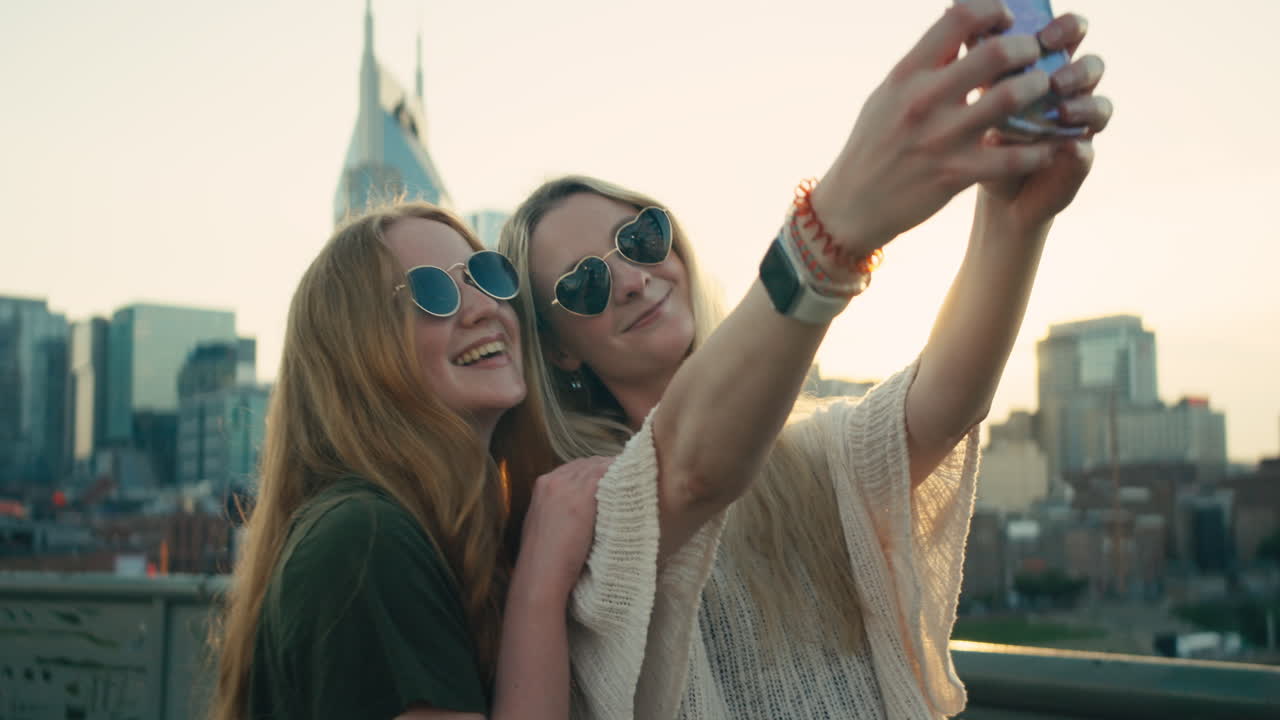 Due donne che si fanno un selfie con uno skyline cittadino sullo sfondo