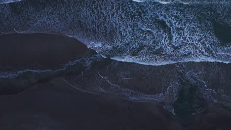 drone aerial view looking straight down over white waves crashing on a beach