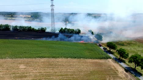grain field burning with red fire and smoke - aerial drone shot