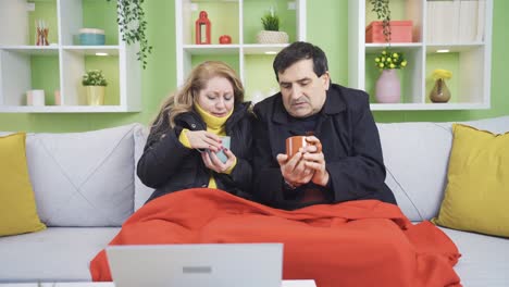 mature couple trying to warm up with hot drink due to cold.