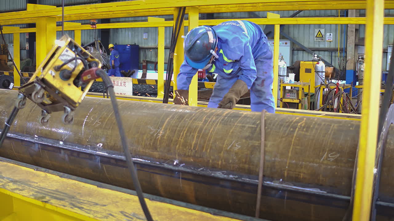 Manual labor worker with PPE on grinding on industrial pipe with sparks flying. Smooth dolly medium shot