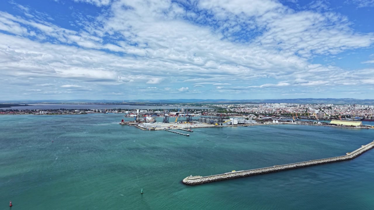 Vista aérea da cidade e da beira-mar, mostrando edifícios, barcos e água em um dia claro próximo à costa.