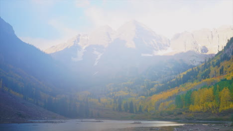 Early-morning-sunrise-close-up-view-Maroon-Bells-Timelapse-fall-colors,-snow,-fog-and-clouds-lifting-by-lake-Aspen-Colorado