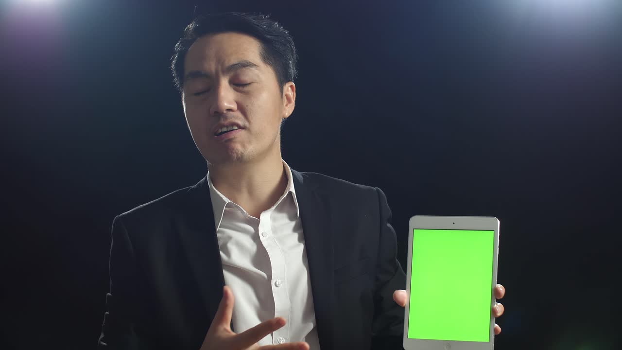 비즈니스맨이 녹색 화면으로 태블릿에서 프레젠테이션을 하고 있습니다.