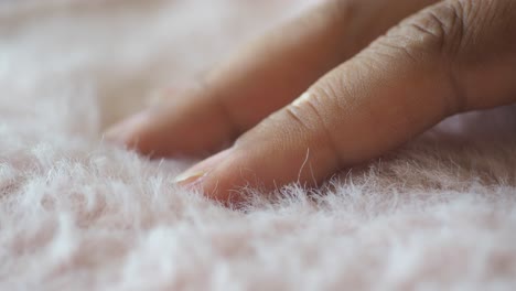 close-up of a hand touching soft, fluffy pink texture