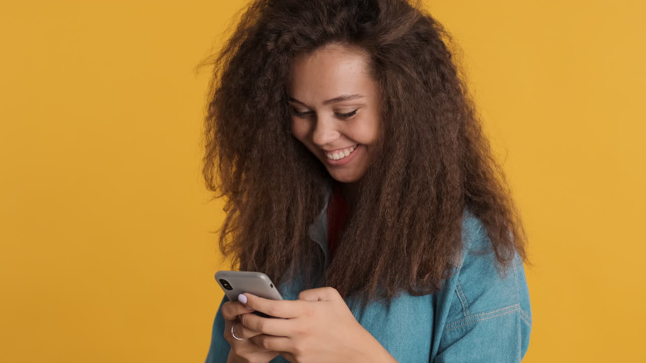 Caucasian curly haired woman texting on smartphone.