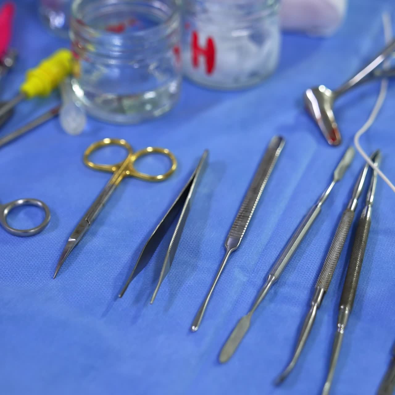 Metal tools, sponges, syringes and vessels at the table with blue sheet. Instruments for rhinoplasty. Close up
