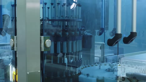 worker woman in uniform works on a vial filling line. production of medical dietary supplements, glass bottles of medicine or vaccine on a conveyor belt product line at pharma factory