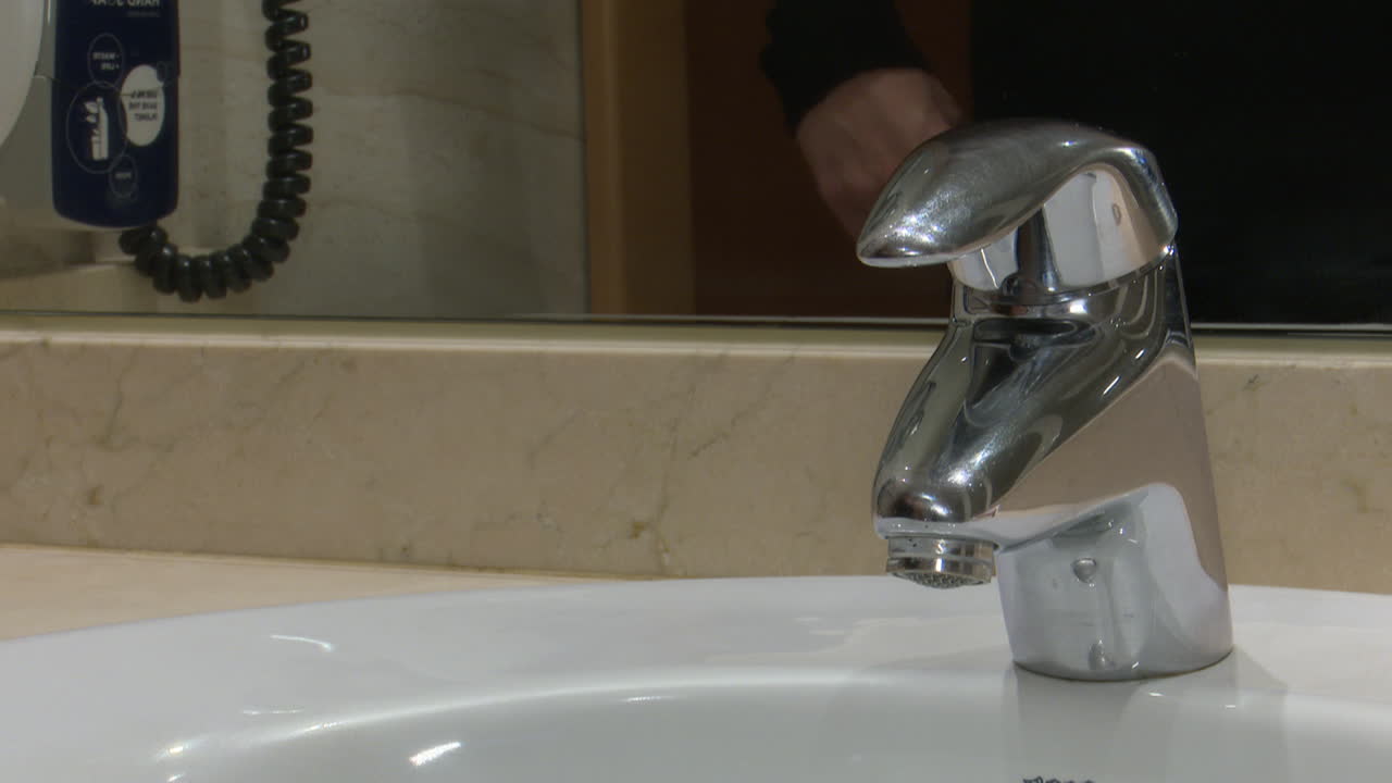 Person turning on bathroom faucet