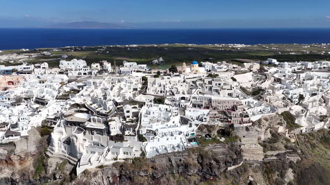 Perspectiva de drone do assentamento empoleirado na caldeira em Santorini, Grécia. Os edifícios brancos criam um contraste marcante contra a paisagem vulcânica escura. Destino de viagem de férias na UE