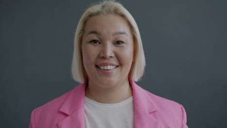 una mujer sonriente con una chaqueta rosa.