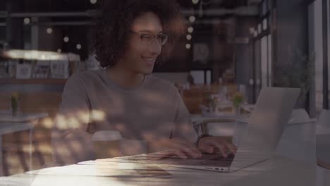 animation of smiling woman using laptop in cafe over sped up commuters walking in city