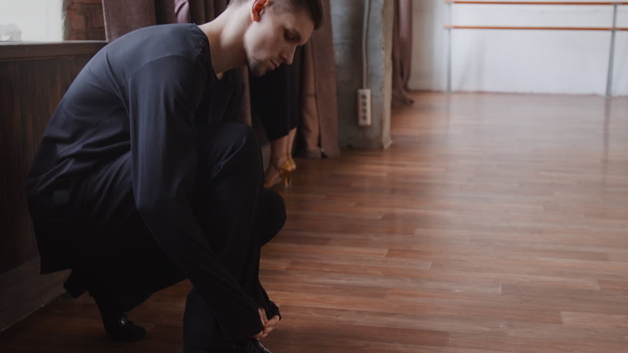 Male dancer tying his shoe in a dance studio