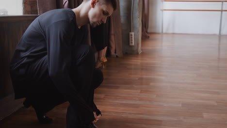 male dancer tying his shoe in a dance studio
